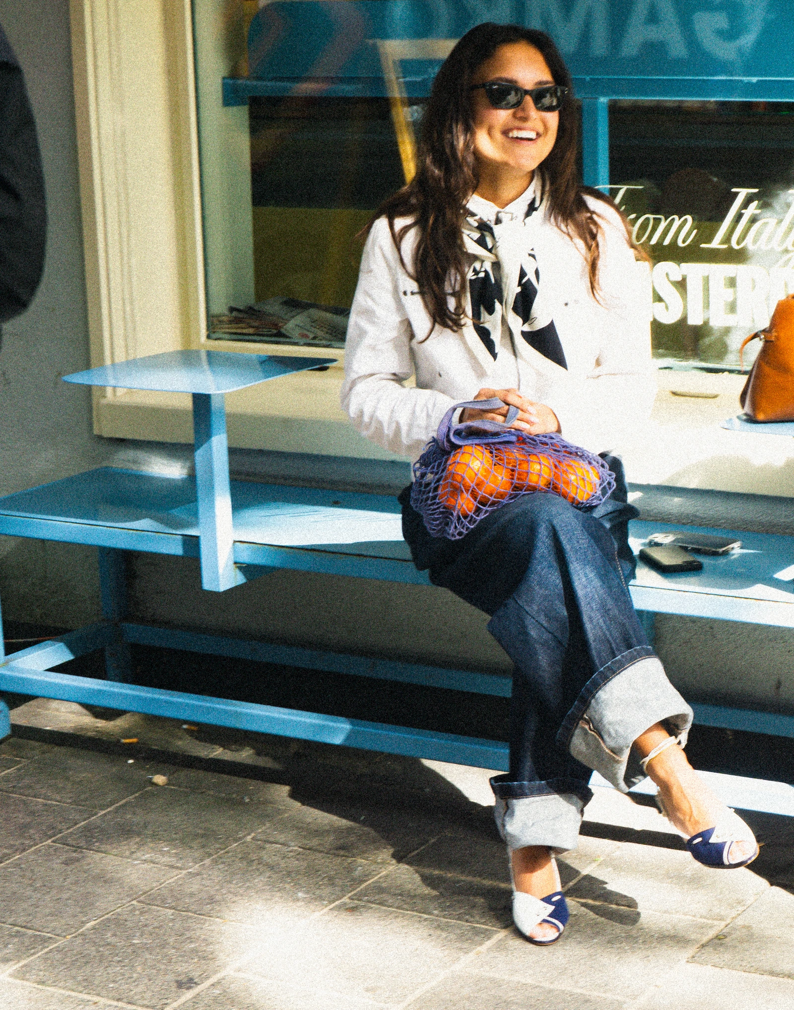The indigo outfit seated with a bag of oranges